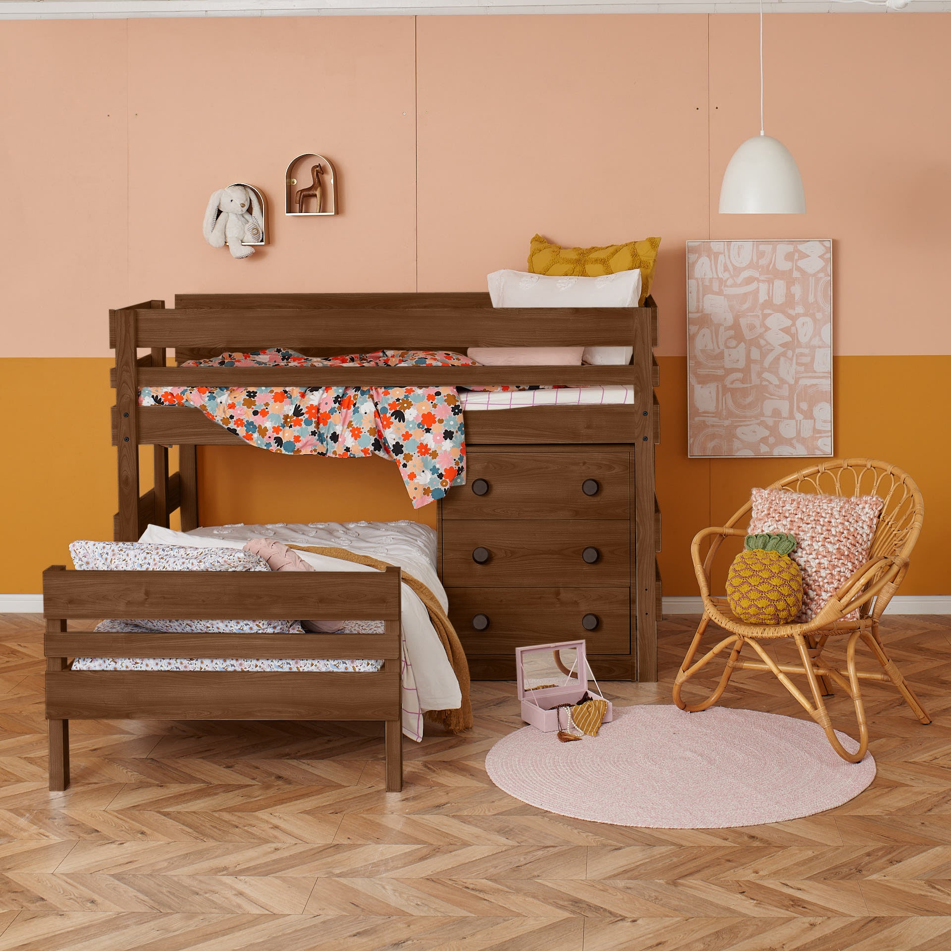 Low height corner bunk bed in native elm with integrated chest drawers, styled with colorful bedding and cozy bedroom decor.