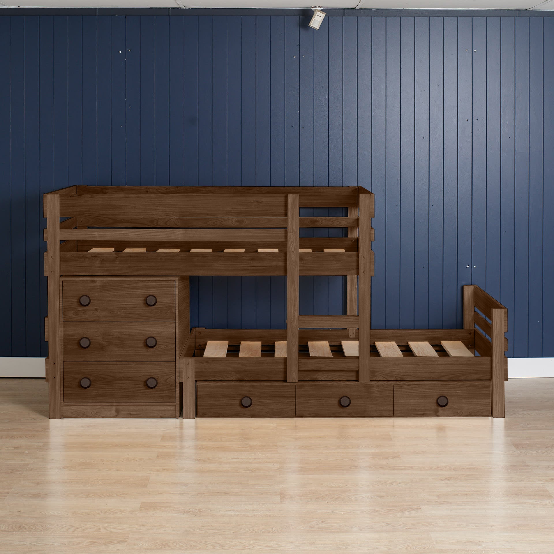 Native elm low height long-wall bunk bed with integrated chest drawers and pull-out trundle on light wood floor.