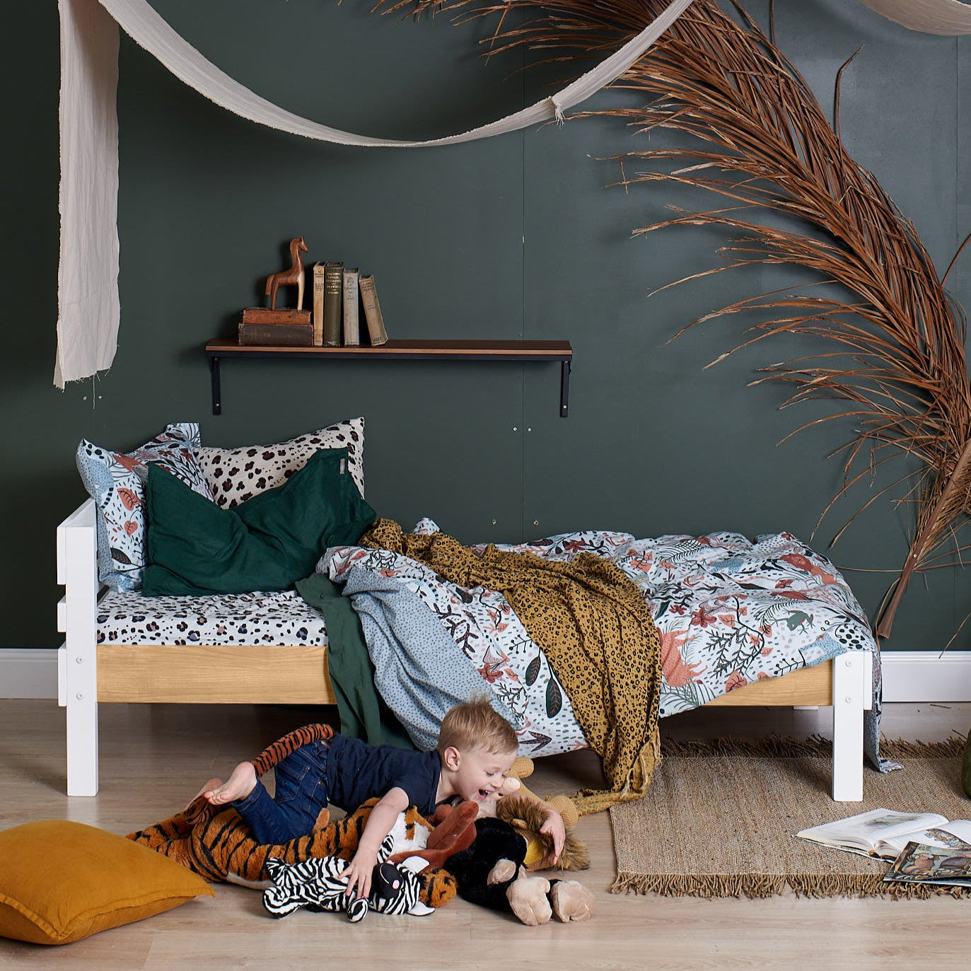 White single bed with floral bedding and green pillows in a modern bedroom setting.