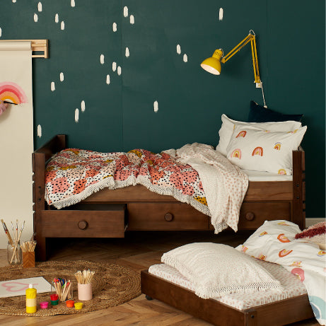 Children's bedroom with wooden bed, drawers, trundle, colourful bedding, and wall decorations in Perth, Australia.