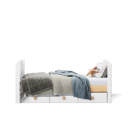 White single captains bed with under bed drawers, layered grey and blue bedding, and decorative pillow.