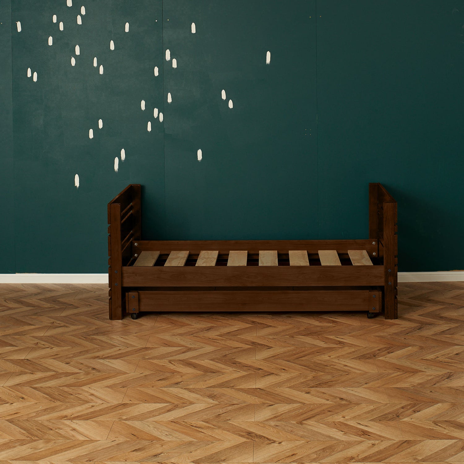 Dark wooden single captains bed frame with slatted base and guard rails against teal wall.