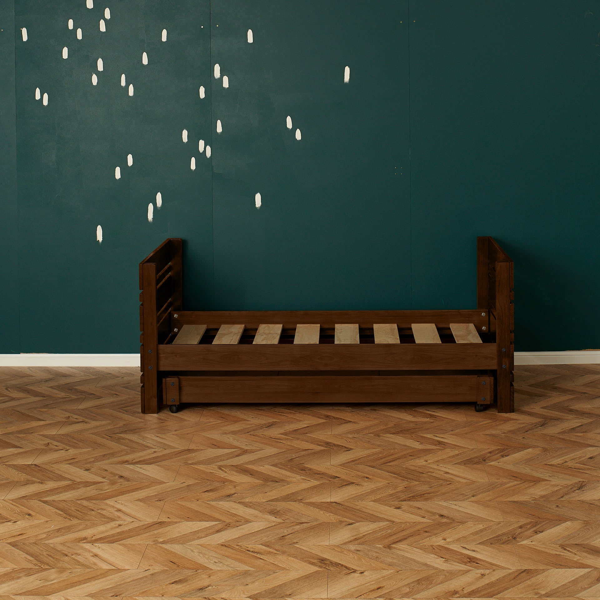 Dark wooden single captains bed frame with slatted base and guard rails against teal wall.