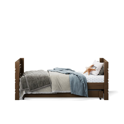 Native elm captains bed with raised panels and bedding including blue and gray throws and white pillow with text.