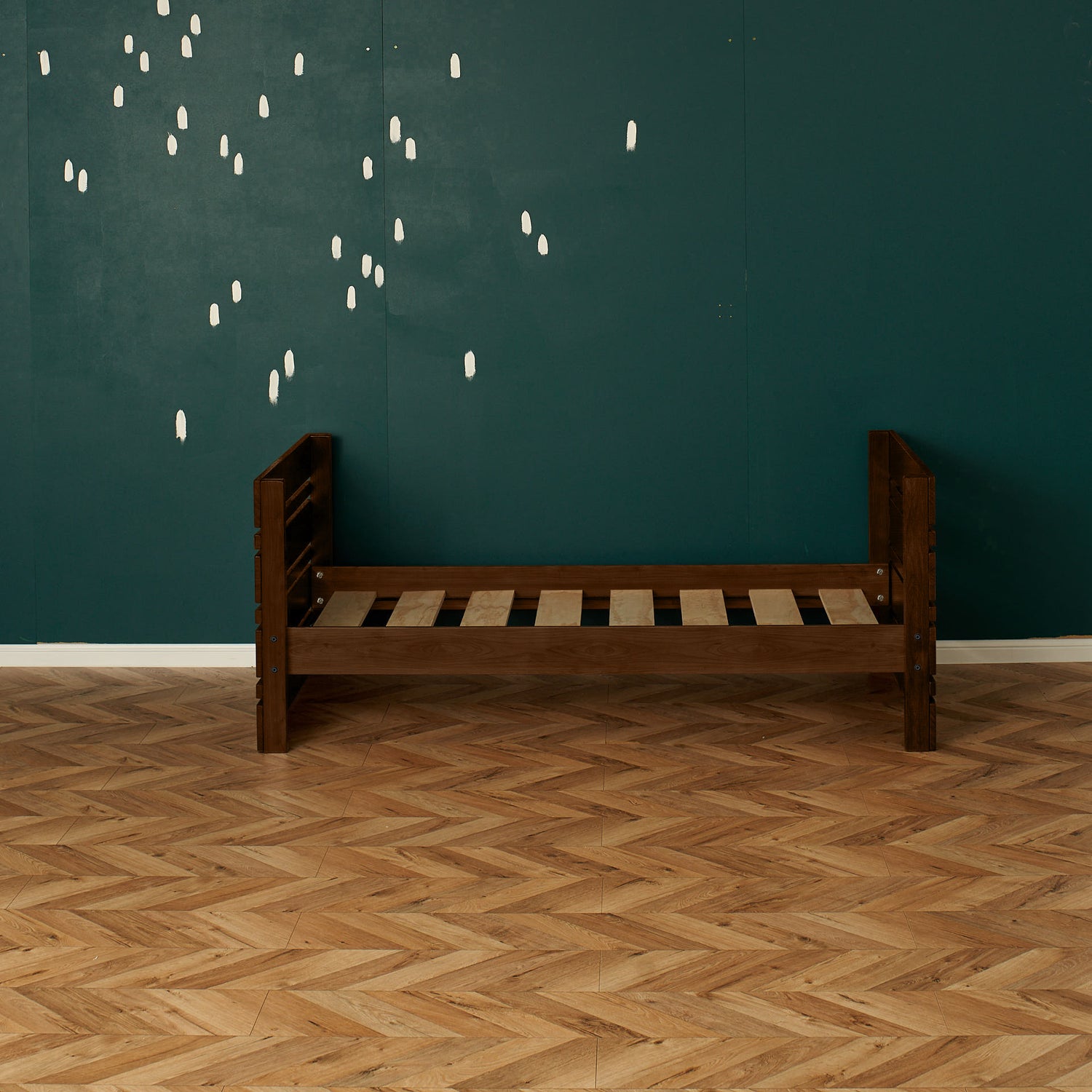 Native elm captains bed frame with slatted base and slatted headboard and footboard against teal wall.