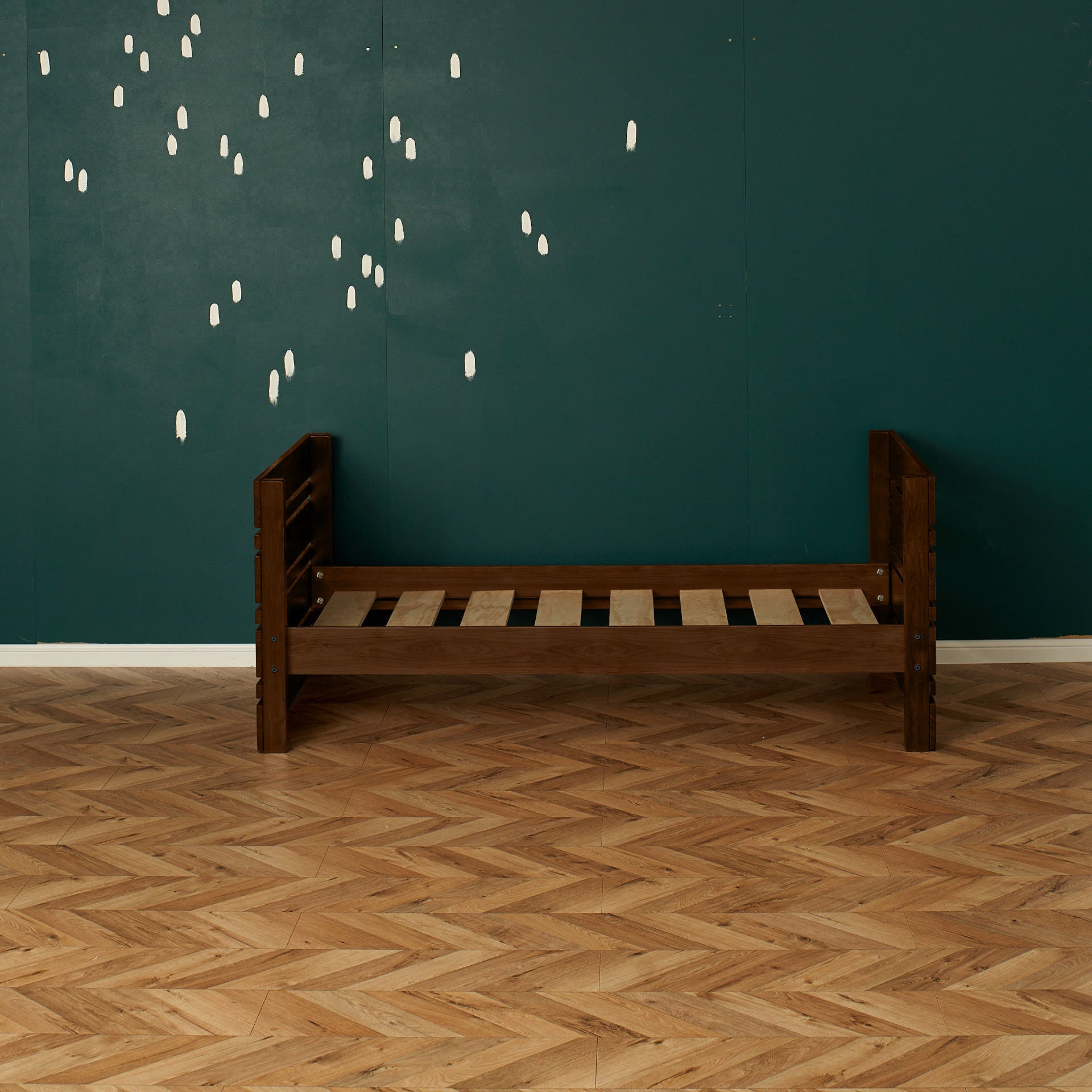 Native elm captains bed frame with slatted base and slatted headboard and footboard against teal wall.