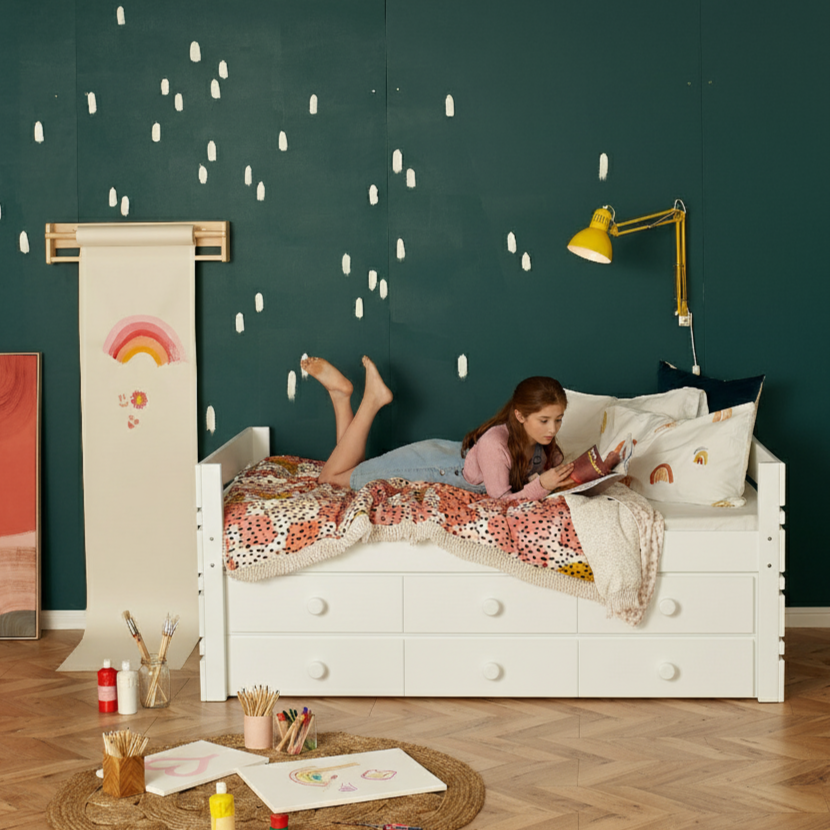 Brisbane girl enjoying magazine lying on white captains bed with extra drawer storage below bed