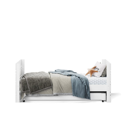 White single captains bed with under bed drawer, layered gray and blue blankets, and decorative pillow.