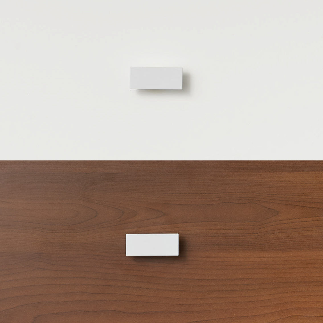White rectangular handle mounted on dark wood panel of bunk bed or loft bed drawer.