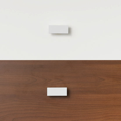 White rectangular handle mounted on dark wood panel of bunk bed or loft bed drawer.