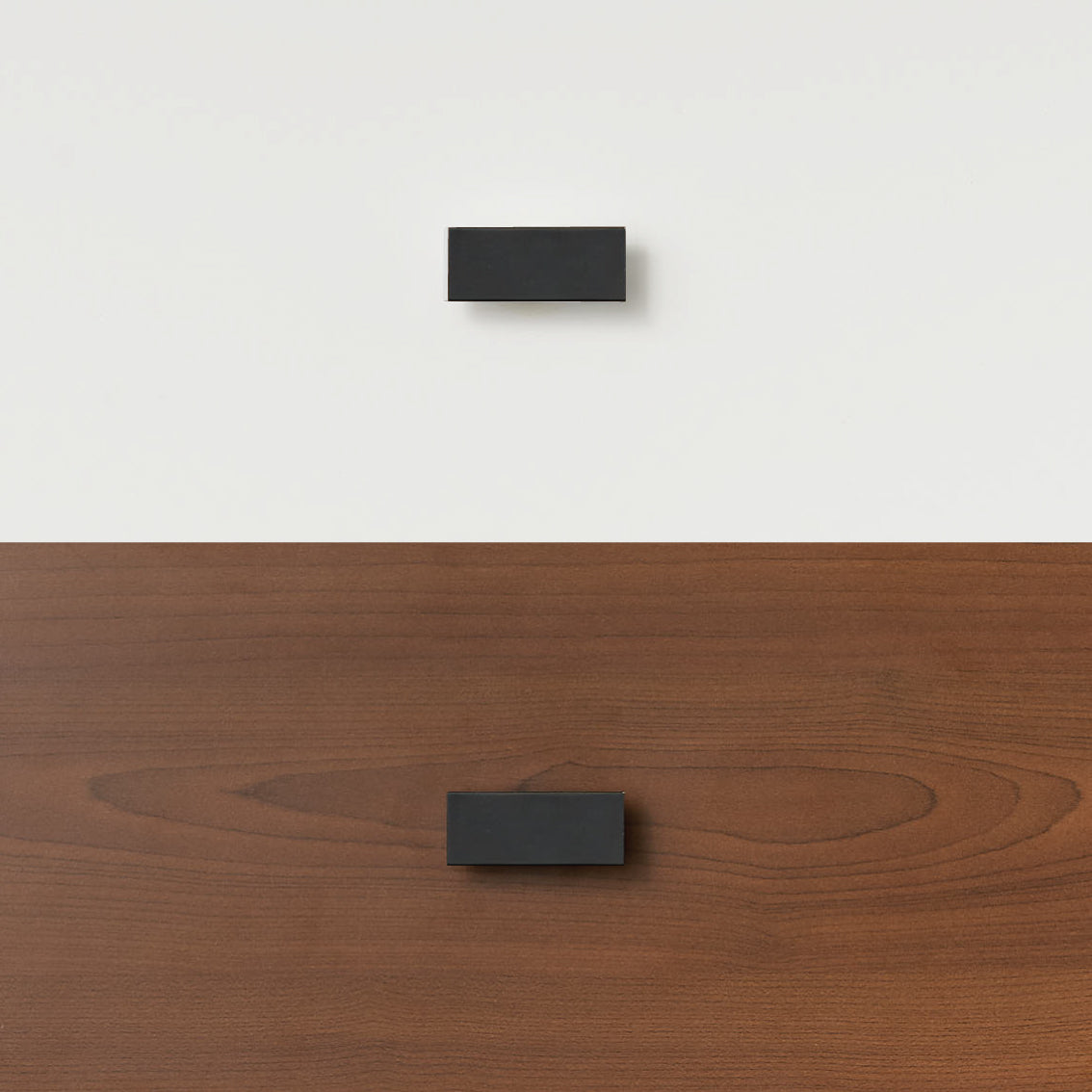 Black timber handle mounted on white wall and matching handle attached to wooden bunk bed panel.