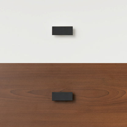 Black timber handle mounted on white wall and matching handle attached to wooden bunk bed panel.