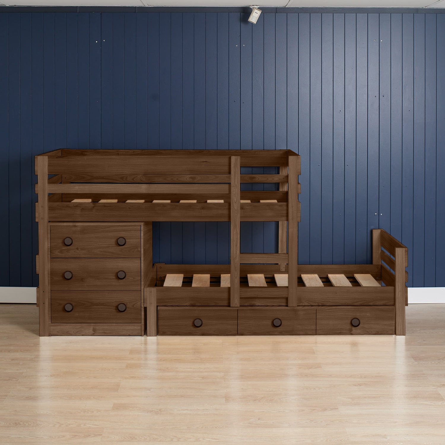 Native elm low height long-wall bunk bed with integrated chest drawers and pull-out trundle on light wood floor.