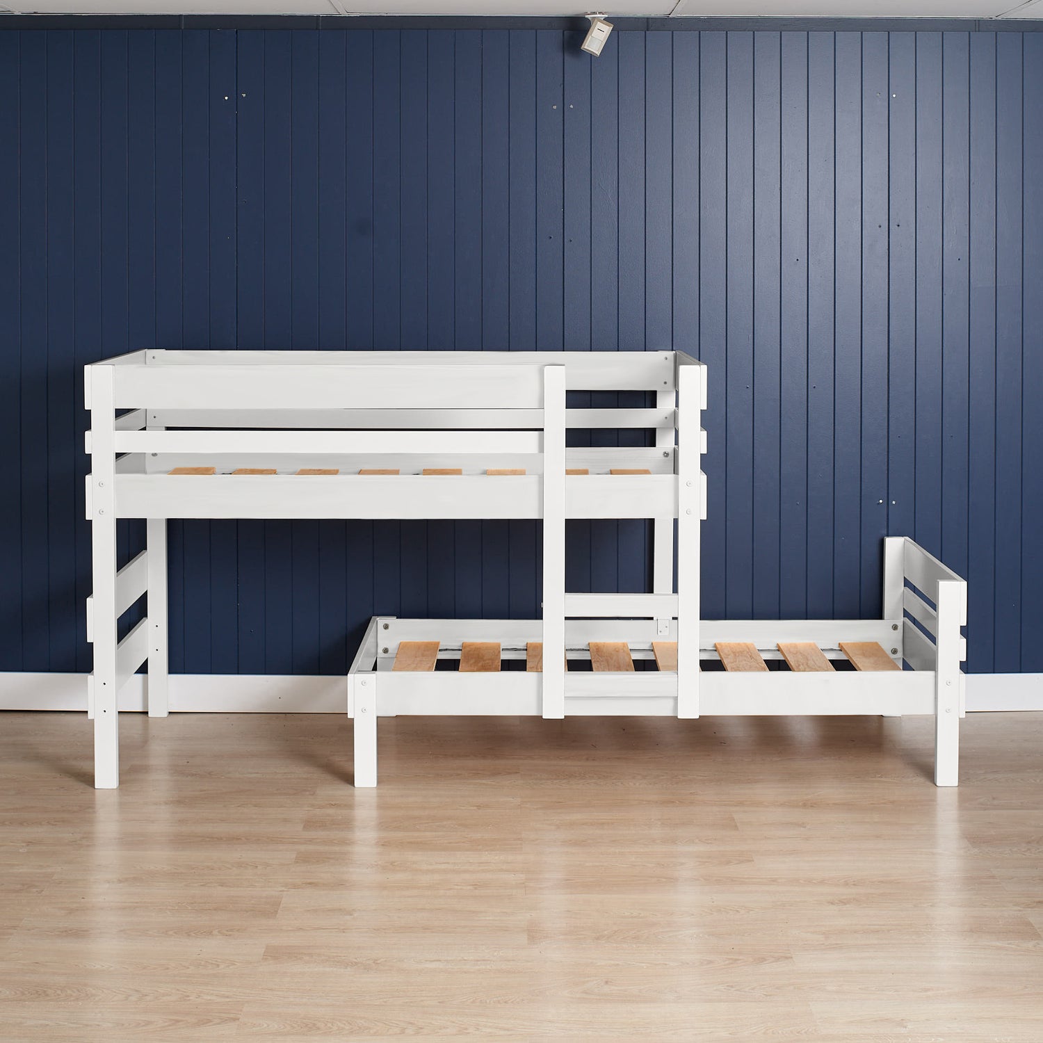 White low height long-wall bunk bed with slatted guardrails and integrated stairs on light wood floor.