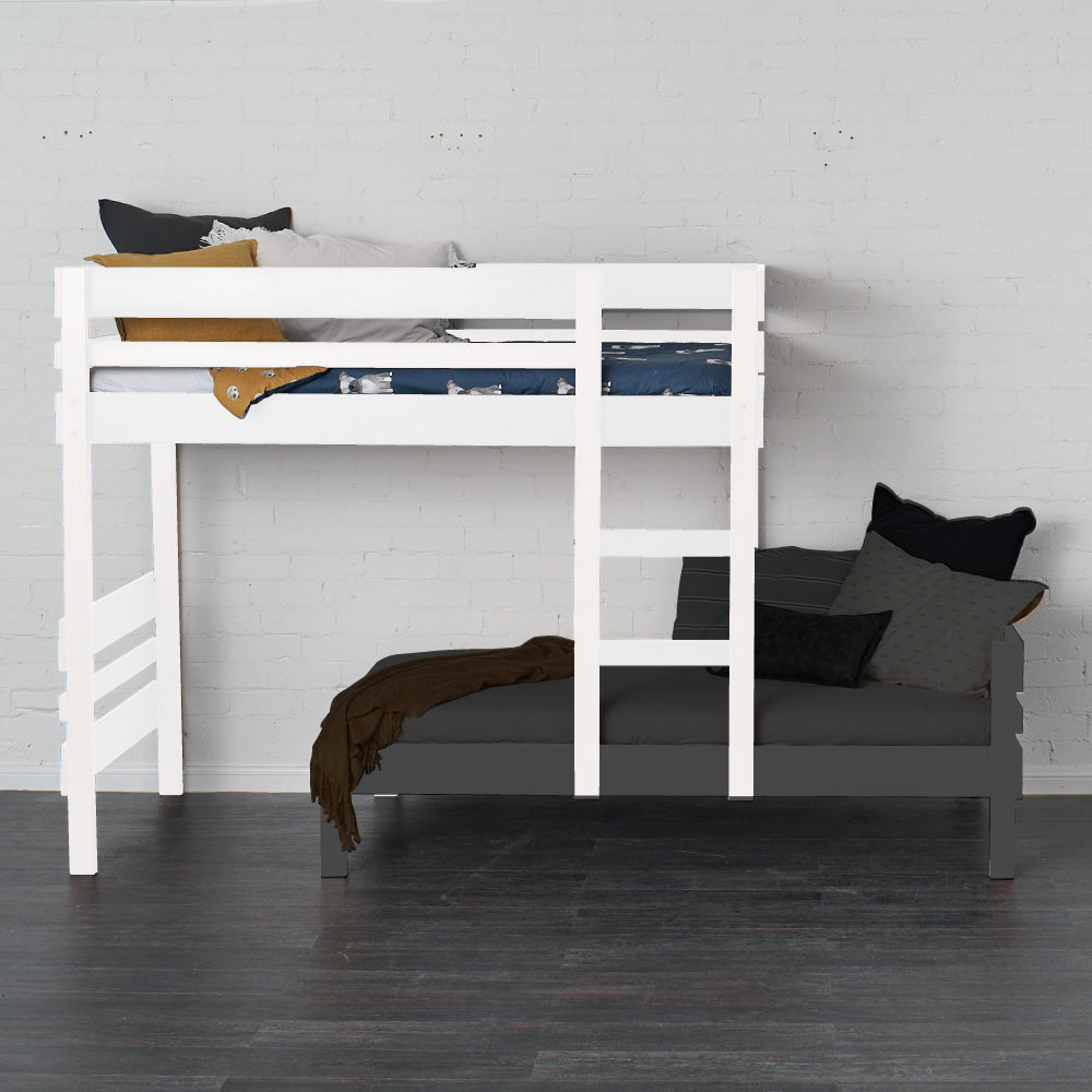 White mid-line loft bed with safety rails and ladder over a dark sofa bed against a white wall.
