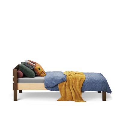 Single wooden bed with low headboard, blue bedding, mustard throw, and decorative pillows.