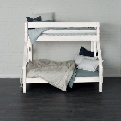 White single over double bunk bed with ladder and bedding against white brick wall.