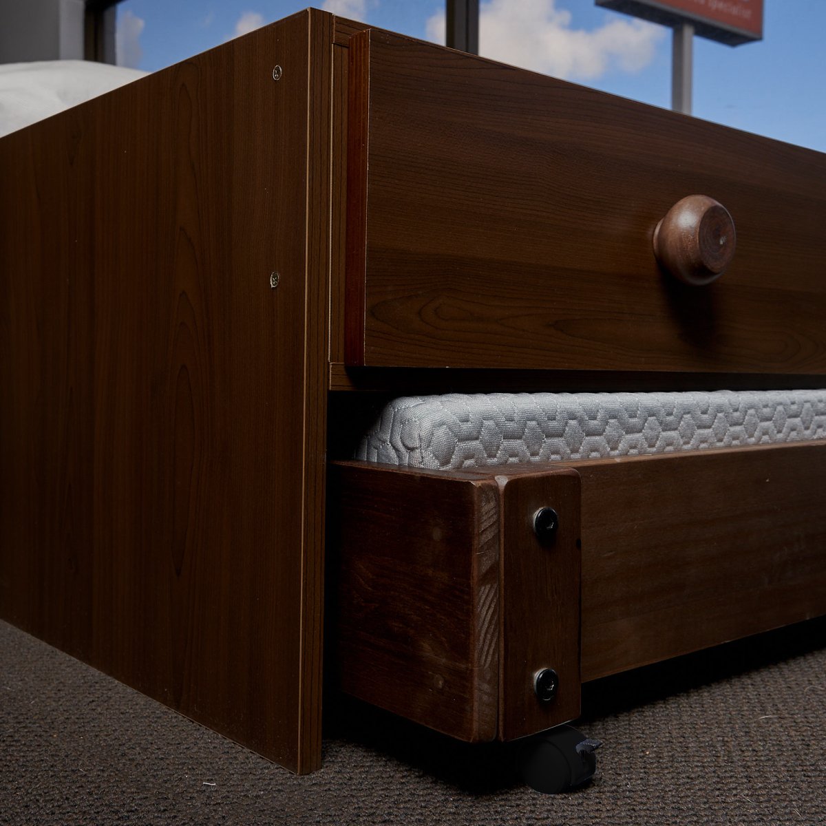 Under bed storage drawers elevated to fit trundle bed below. For use below captain beds. Close up view end plate in Native Elm finish.